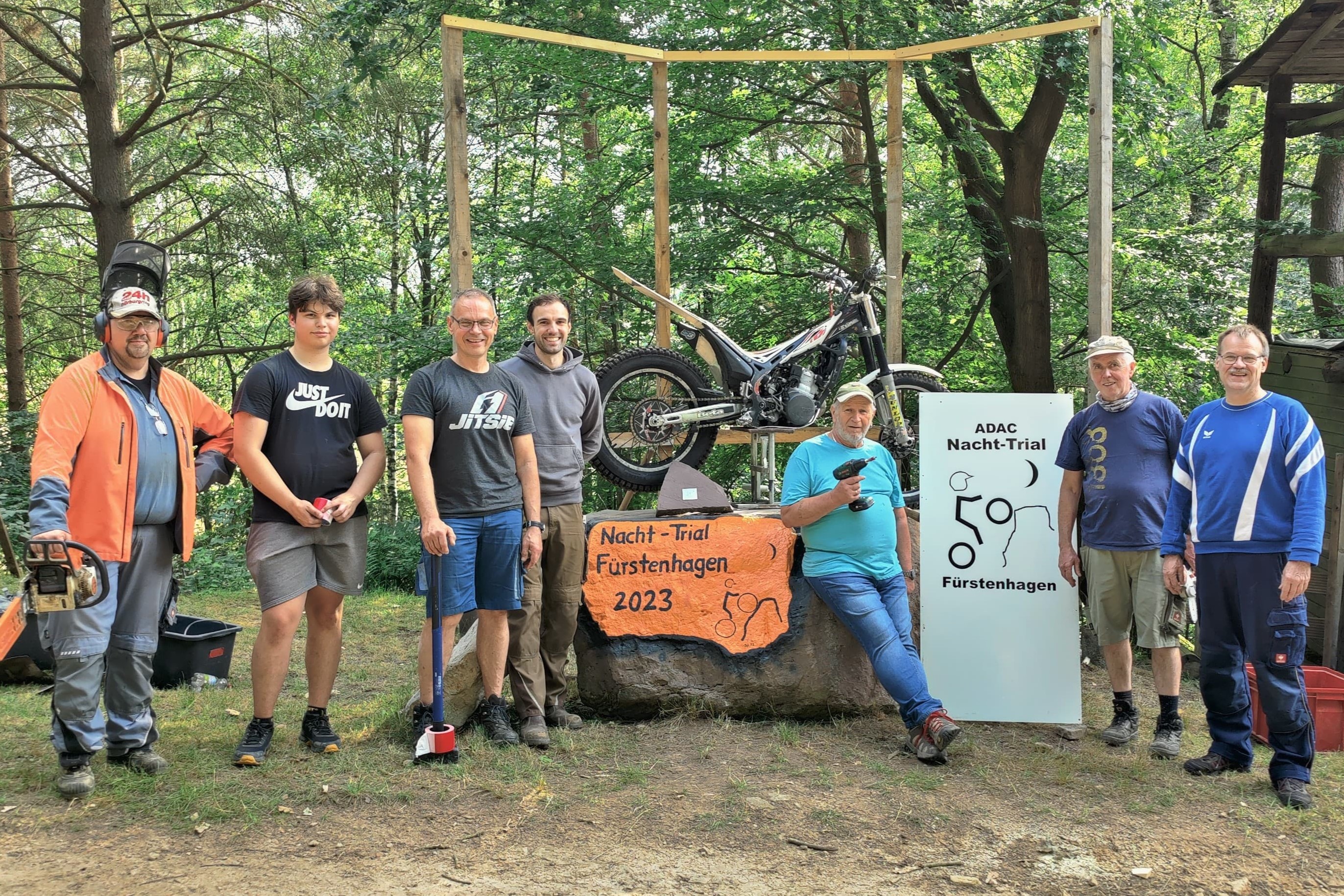 Ein Teil des Aufbau-Teams des MSC Weser-Solling: v.l. Volker Meyer (Sponsoring), Silas Schumann, Torsten Schumann (Streckenchef), Jonas Schulze (2. Vorsitzender), Dieter Engelhardt, Thomas Klepsch (Streckensprecher), Marin Sonsalla (Vorstand Finanzen). In der Mitte die Nacht-Trial-Trophäe aus heimischem Sandstein, gefertigt vom Ex-Nacht-Trial-Piloten Manfred Sustrate (Fürstenhagen). Foto: Frederic Sonne